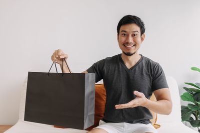Portrait of young man using digital tablet while standing against white background