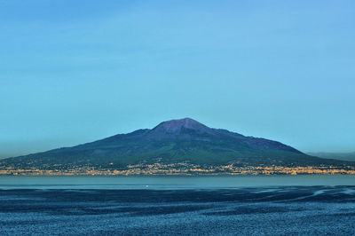 Scenic view of sea and mountains against clear blue sky