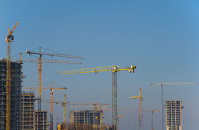 Cranes at construction site against sky