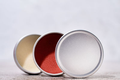 Colorful lip balms in round tin cases on light background with shadow overlay, mockup design, label