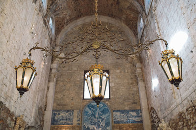 Low angle view of illuminated chandelier hanging from ceiling of building