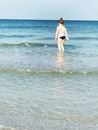 Full length of young woman standing at beach