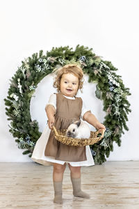 A little girl is holding a basket with a rabbit on the background of christmas decorations. new year