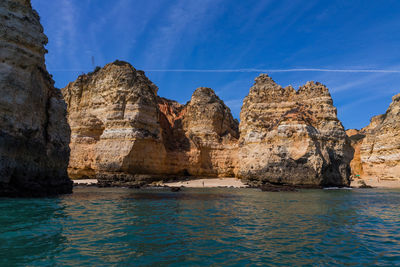 Panoramic view of rock formations in sea against blue sky