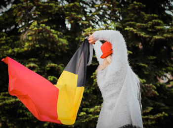 Portrait of a blonde caucasian woman with a hat on her head waving the belgian flag