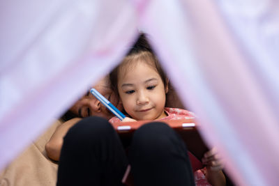 Low angle view of girl sitting on bed