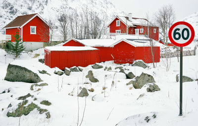 Road sign on snow covered field by building