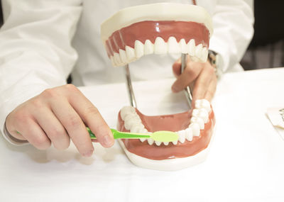 Midsection of woman holding dentures