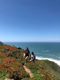 Women sitting on beach against clear sky