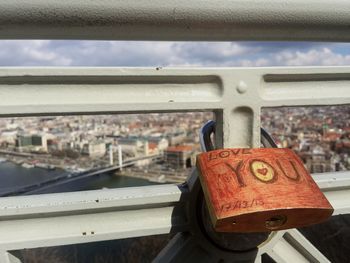 Close-up of padlock with text hanging on railing