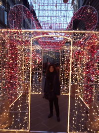 Full length of woman standing in illuminated christmas tree at night