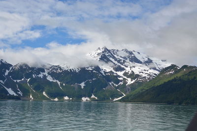 Scenic view of lake by snowcapped mountains against sky