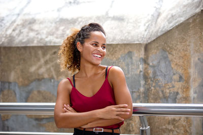 Portrait of smiling young woman standing against wall