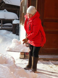  a woman after a heavy snowfall clears the area around a private house from snow with a shovel. 