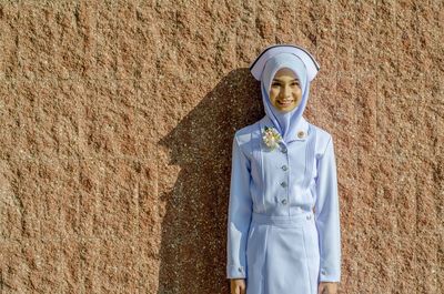 Smiling young woman standing against wall