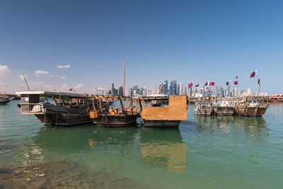 Boats moored at harbor against sky