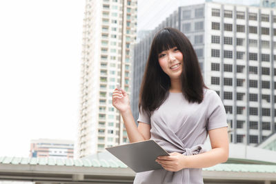 Young businesswoman standing against buildings in city