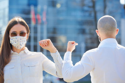 Man and woman wearing mask bumping elbow