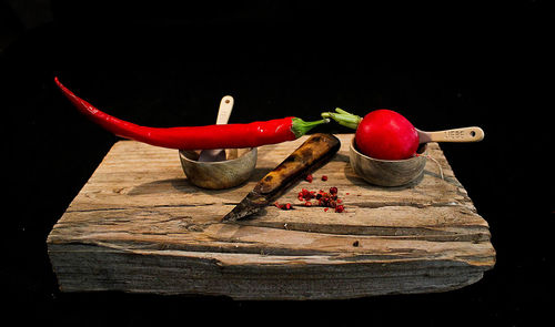 Close-up of red chili peppers on table against black background