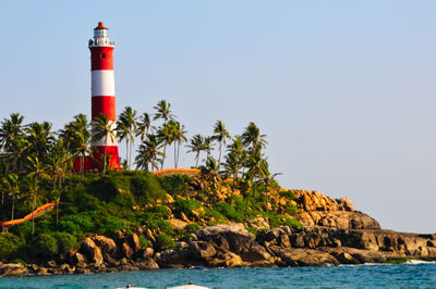 Lighthouse by sea against clear sky