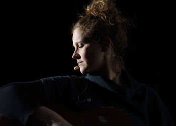 Portrait of teenage girl looking away against black background