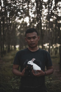 Portrait of young man holding tree