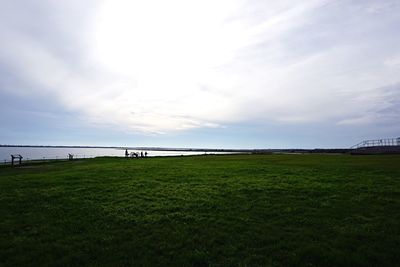 Scenic view of grassy field against cloudy sky