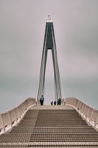 Low angle view of people on bridge against sky