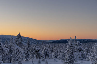 Scenic view of snow covered land against sky during sunset