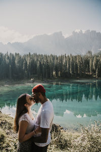 Side view of couple kissing in lake against mountains