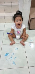 Portrait of cute boy sitting on floor at home