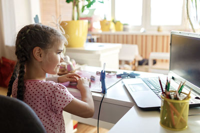 Girl making decoration while learning over laptop on table