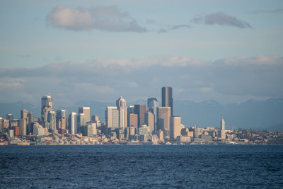 Sea by cityscape against sky