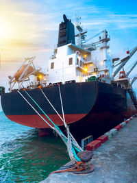 Ship moored at harbor against sky