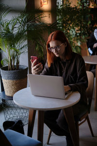 Young woman using mobile phone while sitting at outdoor cafe