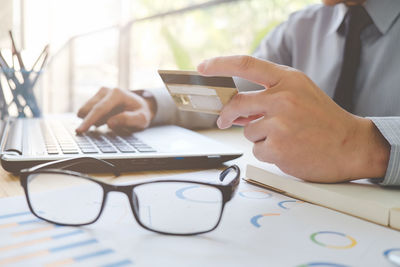 Midsection of man using laptop on table