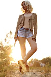 Full length of woman standing on field against sky during sunset