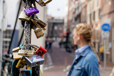 Close-up of padlocks hanging on railing with woman standing in background