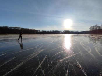 Man standing on lake against sky during winter