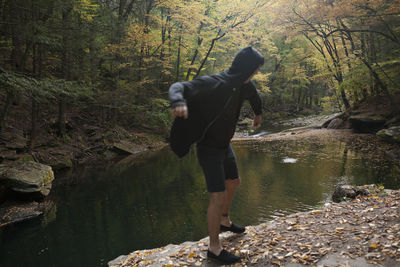 Rear view of man walking by stream in forest