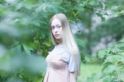 Portrait of young woman standing against plants