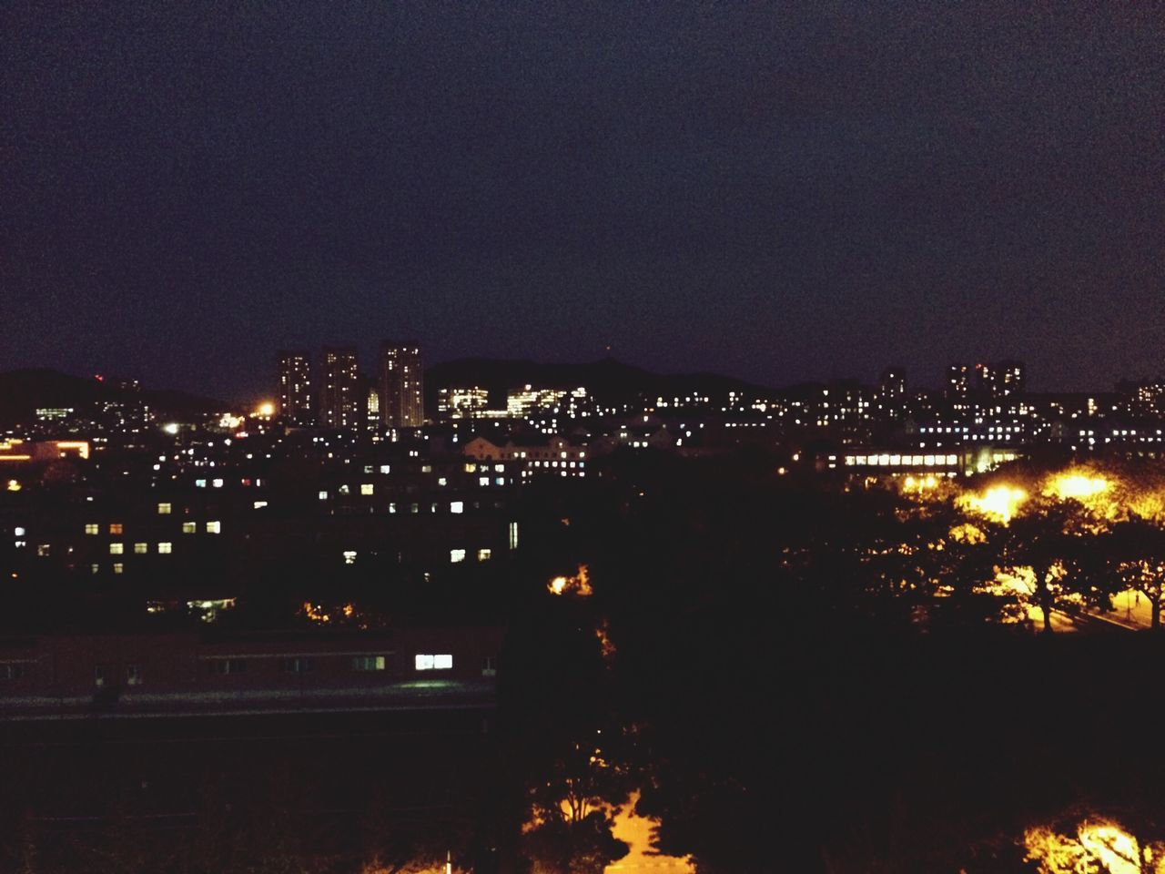 illuminated, night, building exterior, architecture, built structure, city, cityscape, dark, residential building, residential structure, copy space, high angle view, sky, residential district, light - natural phenomenon, lighting equipment, clear sky, glowing, house, no people