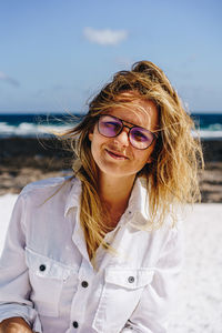 Portrait of woman wearing sunglasses standing at beach