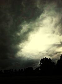Silhouette of trees against cloudy sky