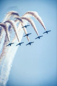 Low angle view of airplanes flying against clear blue sky