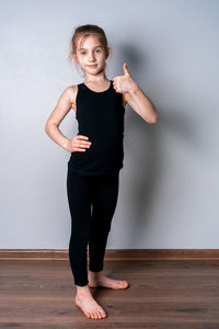 Portrait of young woman standing against wall