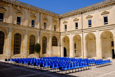 Row of people in illuminated building against clear blue sky