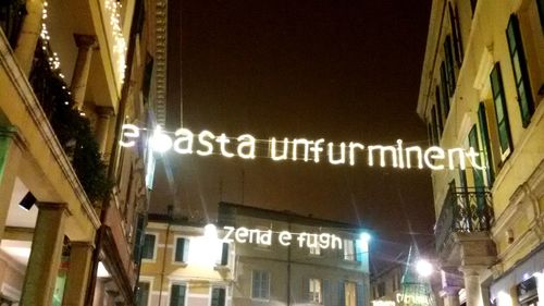 Low angle view of illuminated text in city at night