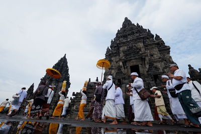 Low angle view of people by buildings against sky