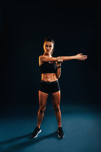 Female athlete stretching against black background